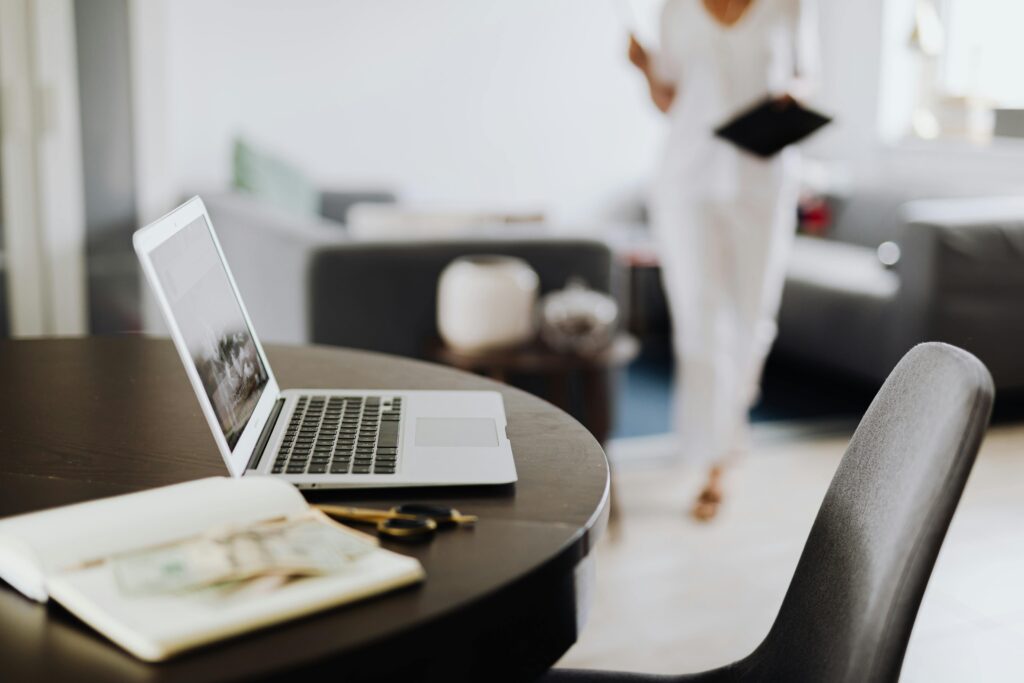 Contemporary workspace featuring laptop, notebook, and blurred person in office setting.